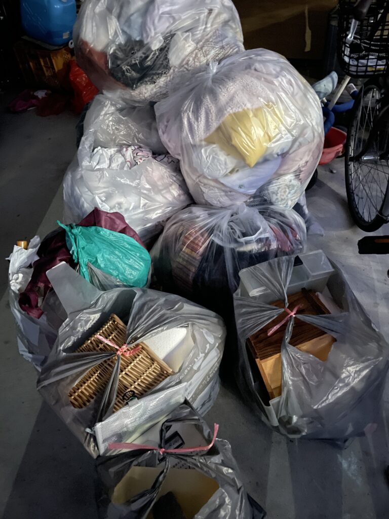 Several large garbage bags filled with clothes, household items, and debris during room renovation for health spa transformation