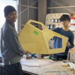 Two students holding a parametric design panel in a workshop, showcasing the process of digital fabrication in architecture