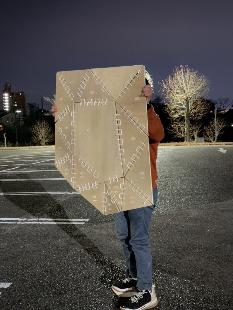 Student holding a digitally fabricated panel with interlocking joints, showcasing parametric design techniques for architectural applications