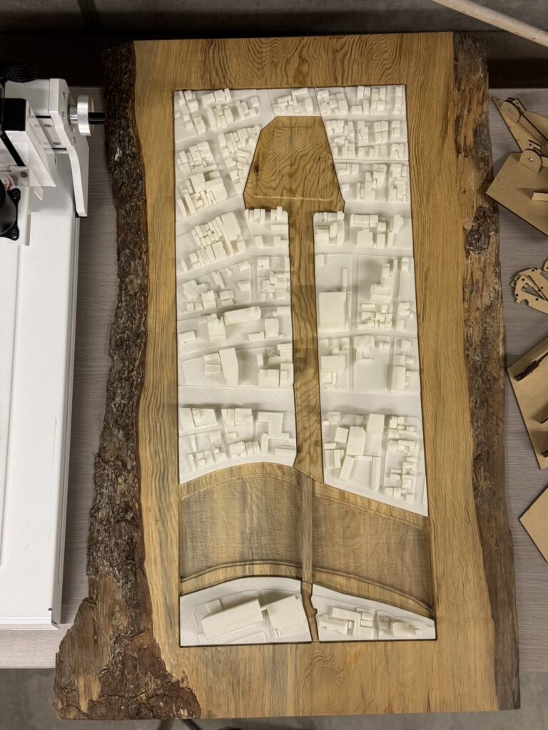 Architectural site model with 3D-printed structures mounted on a CNC-machined natural wood base, showcasing urban planning and design precision