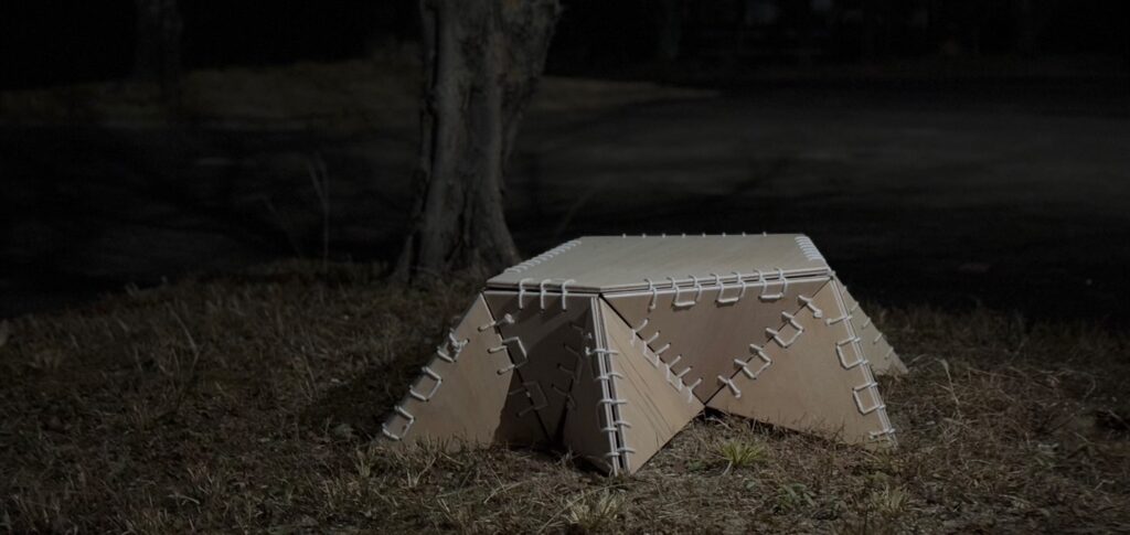 Digitally fabricated stool designed with interlocking joints, displayed outdoors under dim lighting