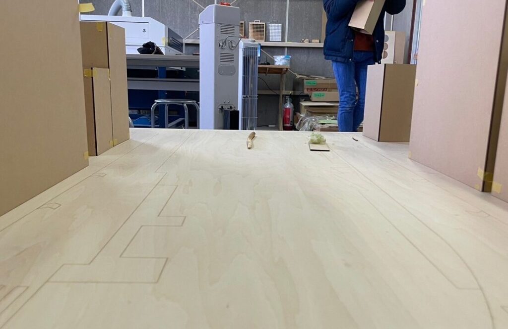 Architect working in a fabrication studio with a CNC-machined wooden panel featuring intricate design outlines